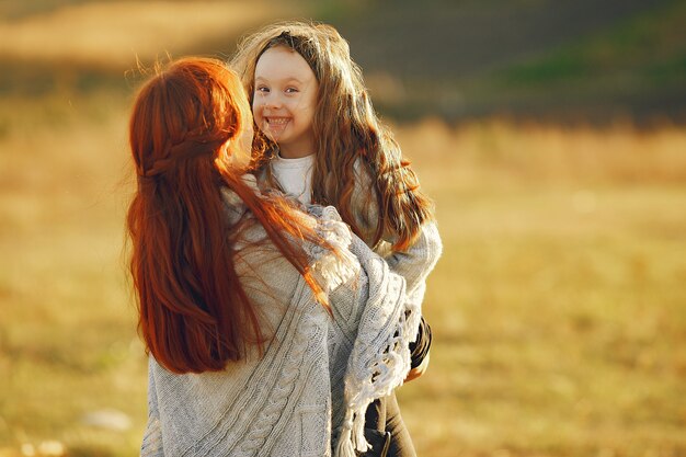 Madre con hija pequeña jugando en un campo de otoño