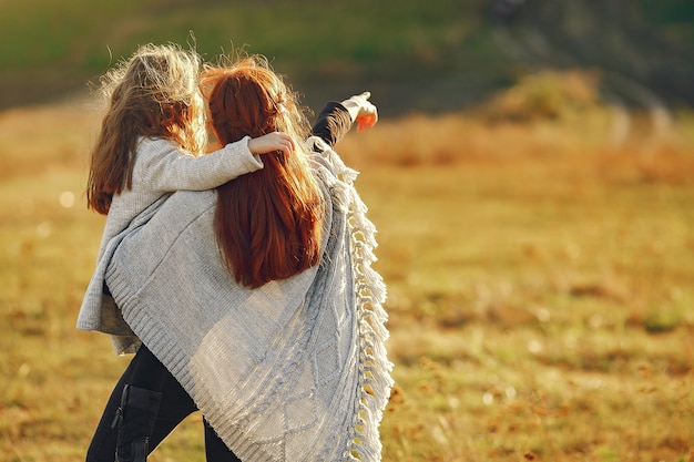 Madre con hija pequeña jugando en un campo de otoño