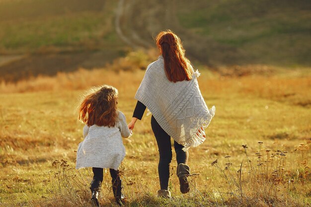 Madre con hija pequeña jugando en un campo de otoño