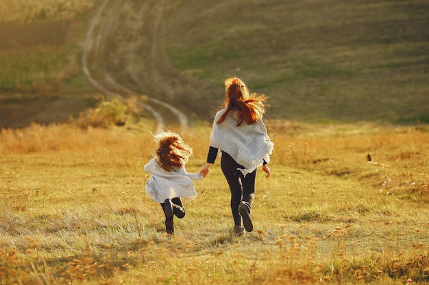 Madre con hija pequeña jugando en un campo de otoño