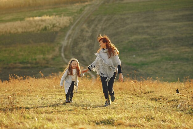 Madre con hija pequeña jugando en un campo de otoño