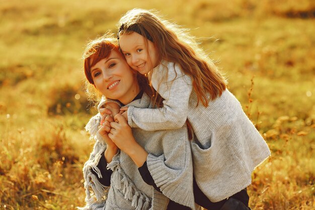 Madre con hija pequeña jugando en un campo de otoño