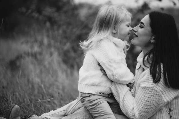 Madre con hija pequeña juntos en clima otoñal divirtiéndose