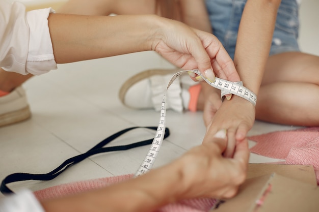 Madre con hija pequeña medir la tela para coser