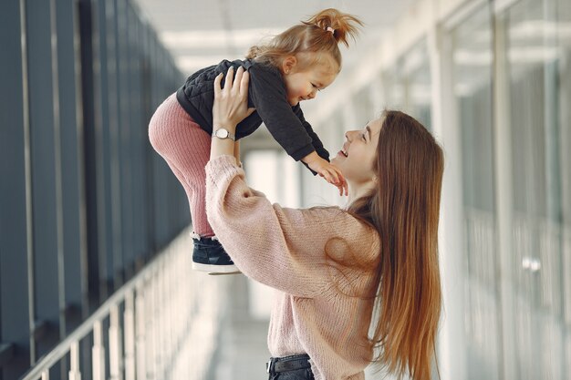 Madre con hija pequeña de pie en un pasillo