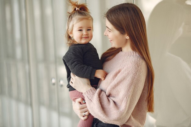 Madre con hija pequeña de pie en un pasillo