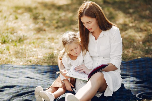 Madre con hija pequeña sentada en una tela escocesa y leer el libro