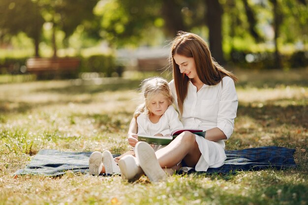 Madre con hija pequeña sentada en una tela escocesa y leer el libro