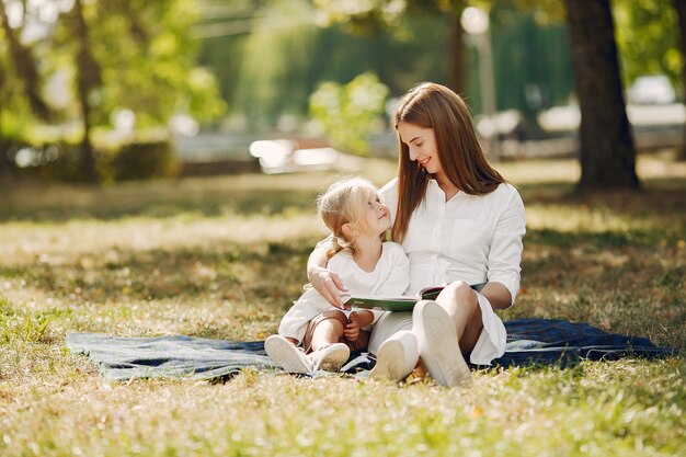 Madre con hija pequeña sentada en una tela escocesa y leer el libro
