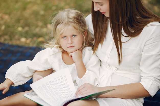 Madre con hija pequeña sentada en una tela escocesa y leer el libro