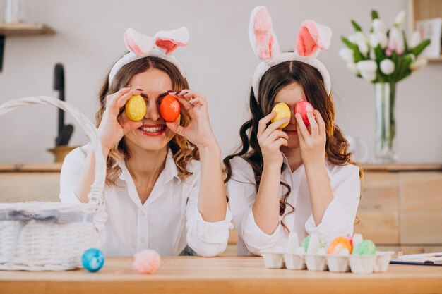 Madre con hija pintando huevos para pascua