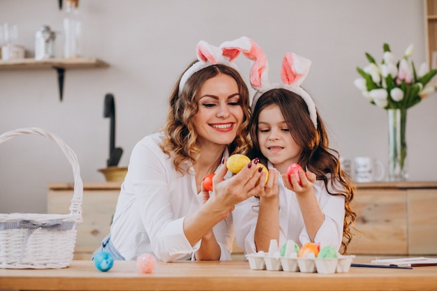 Madre con hija pintando huevos para pascua