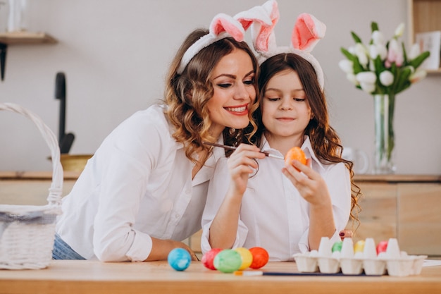 Madre con hija pintando huevos para pascua