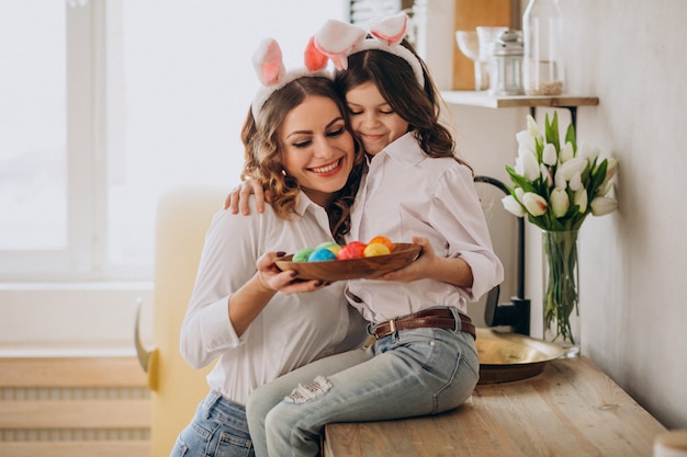 Madre con hija pintando huevos para pascua