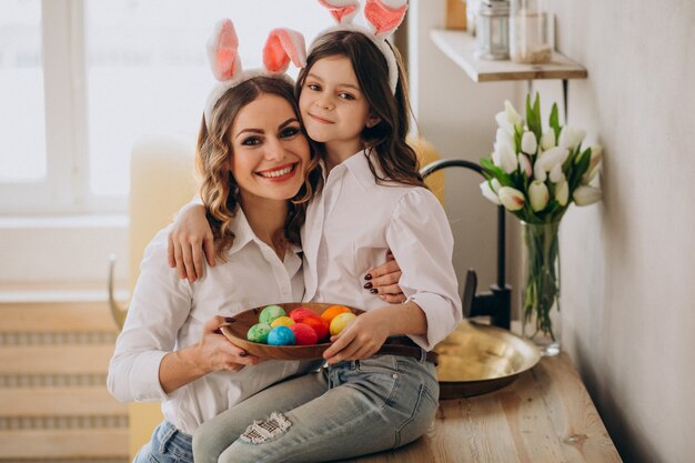 Madre con hija pintando huevos para pascua