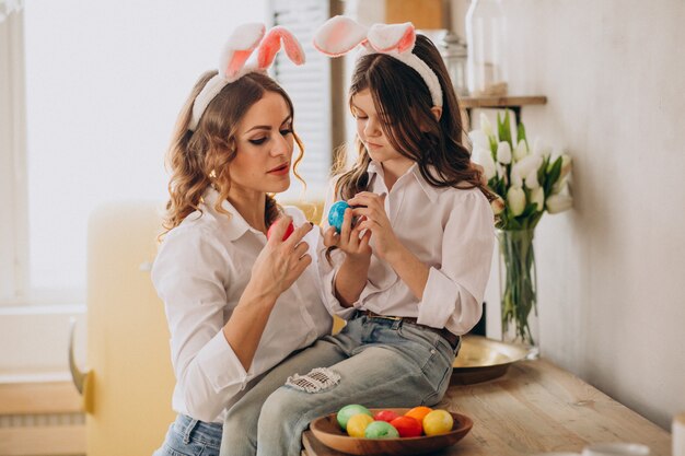 Madre con hija pintando huevos para pascua