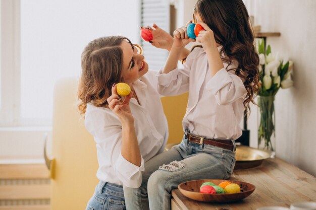 Madre con hija pintando huevos para pascua