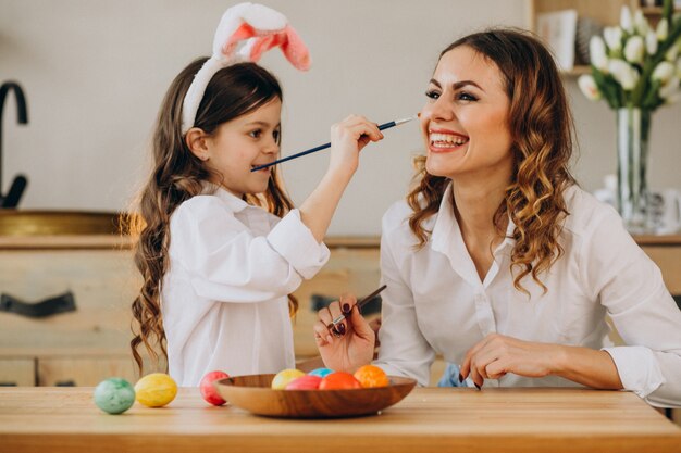 Madre con hija pintando huevos para pascua