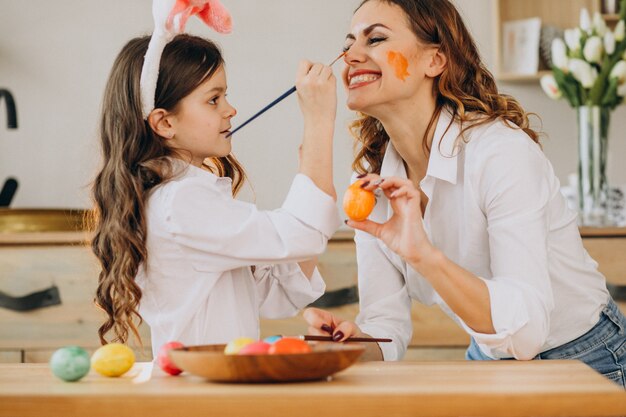 Madre con hija pintando huevos para pascua