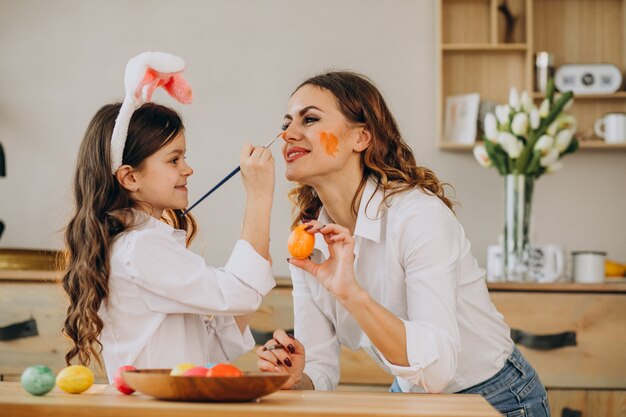 Madre con hija pintando huevos para pascua