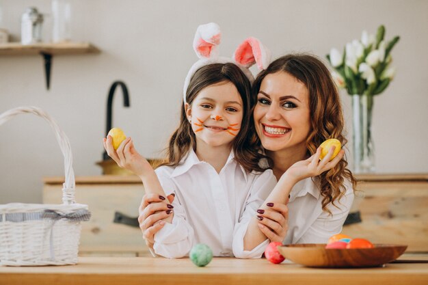 Madre con hija pintando huevos para pascua