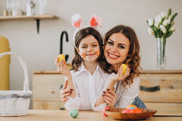 Madre con hija pintando huevos para pascua