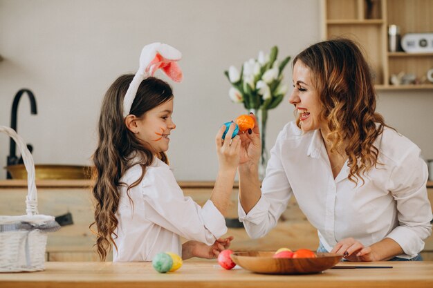 Madre con hija pintando huevos para pascua