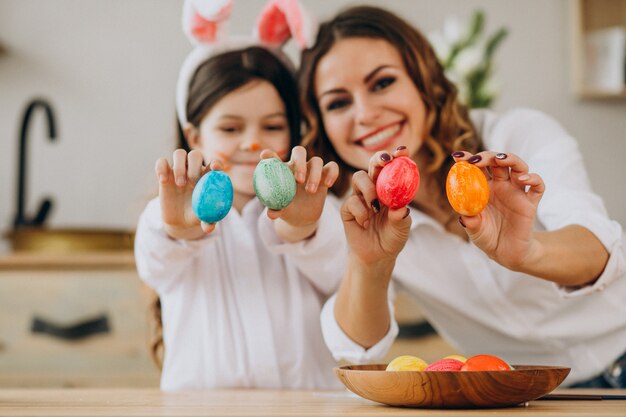 Madre con hija pintando huevos para pascua
