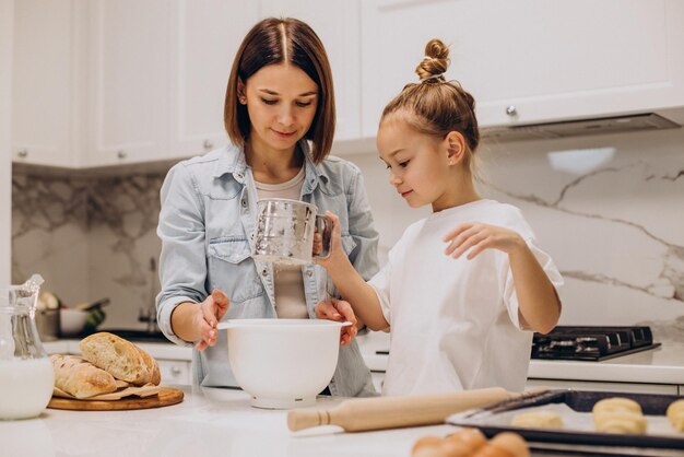 Madre con hija preparando masa para hornear