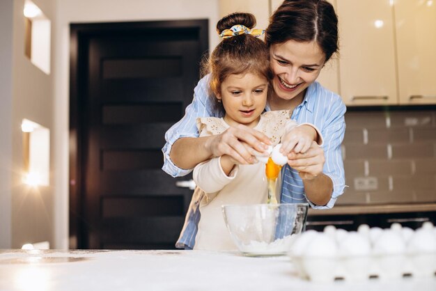 Madre con hija preparando masa para hornear