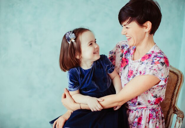 La madre con la hija que abraza y que se sienta en la silla