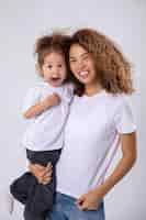 Foto gratuita madre y hija rizadas posando en un fondo blanco con camisetas blancas