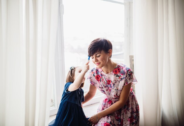 La madre con hija sentada en el alféizar de la ventana