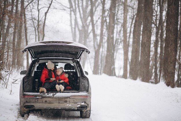 Madre con hija sentada en coche en invierno