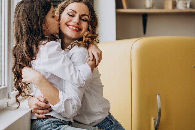 Madre con hija sentada en la cocina