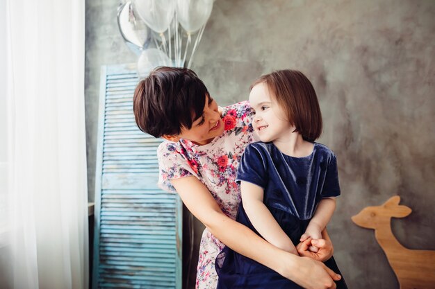 La madre con la hija sentada en la escalera y manteniendo los globos