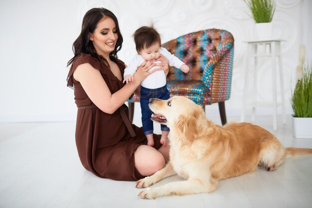 La madre con hija sentada en el suelo y mirando perro