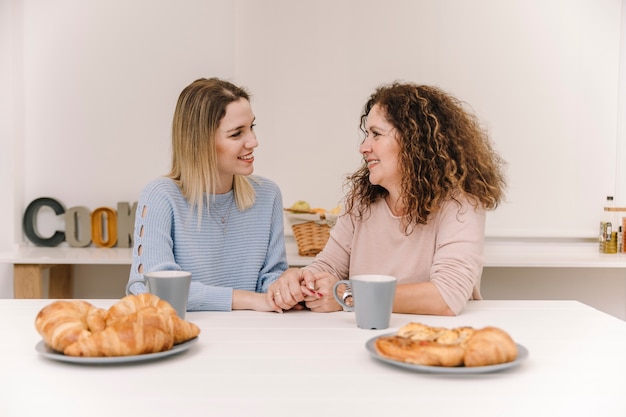 Madre y hija tomados de la mano durante el desayuno