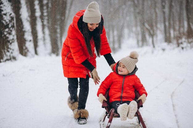 Madre con hija en trineo de parque de invierno