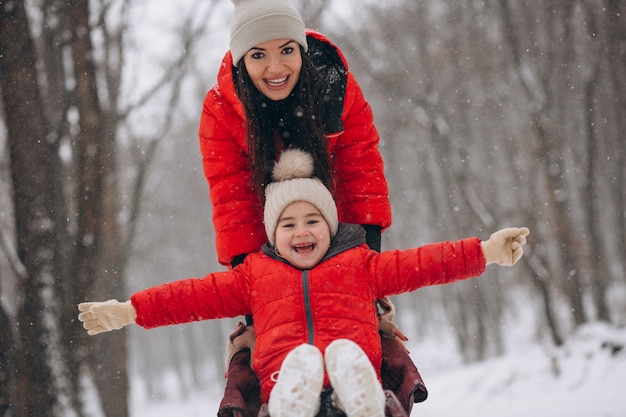 Madre con hija en trineo de parque de invierno