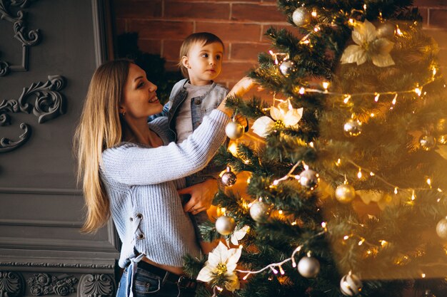 Madre con hijita decorando arbol de navidad