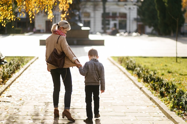 madre con hijo caminando al aire libre en otoño