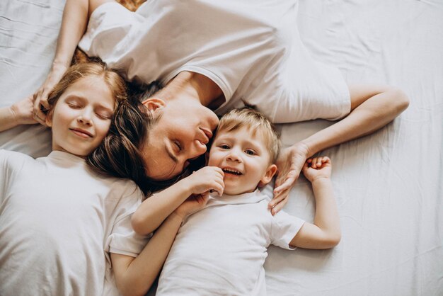 Madre con hijo e hija divirtiéndose en la cama