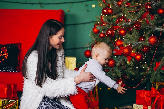 Madre con hijo junto al arbol de navidad.