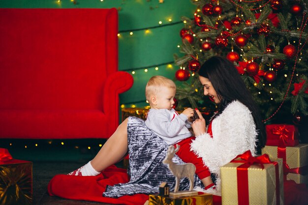 Madre con hijo junto al arbol de navidad.