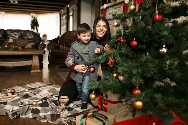 Foto gratuita madre con hijo en navidad por el abeto