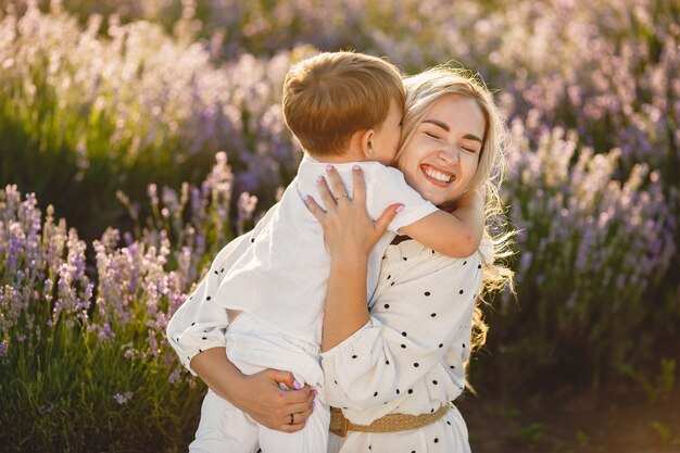 Madre con hijo pequeño en campo de lavanda. Mujer hermosa y lindo bebé jugando en el campo del prado. Vacaciones familiares en verano.