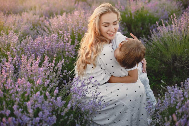 Madre con hijo pequeño en campo de lavanda. Mujer hermosa y lindo bebé jugando en el campo del prado. Vacaciones familiares en verano.