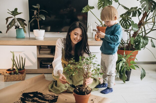 Madre con hijo pequeño cultivando plantas en casa