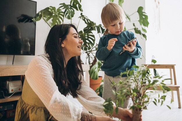 Madre con hijo pequeño cultivando plantas en casa